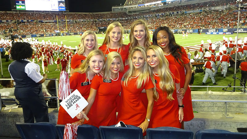 Capstone women pose for a photo in a stadium.
